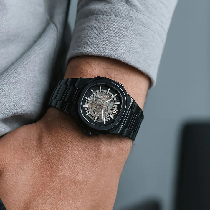 Black wristwatch on a person's wrist with a blurred background