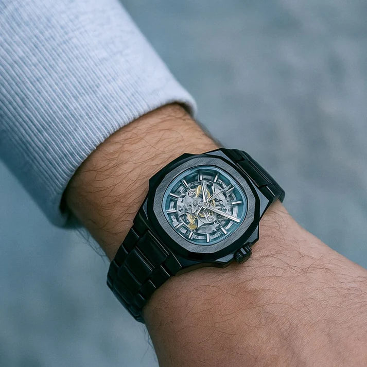 Black wristwatch with a detailed face on a wrist, blurred background